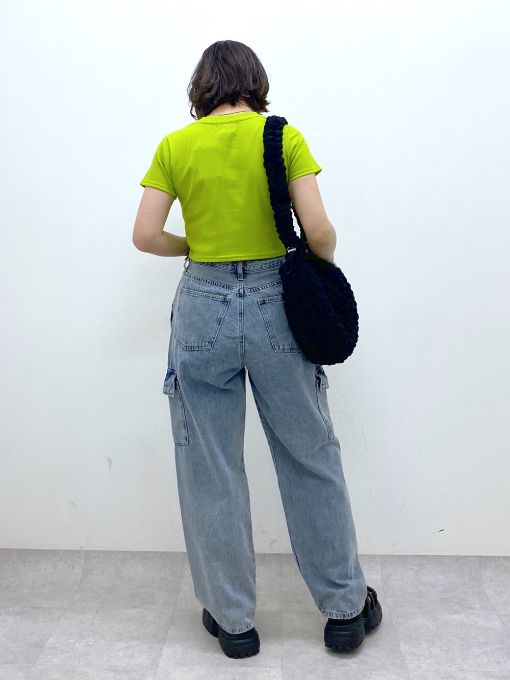 ブルー系のデニムパンツ、ブラック系のバッグ、イエロー系のTシャツ/カットソーを着用したレディースの春コーディネートの4枚目の写真