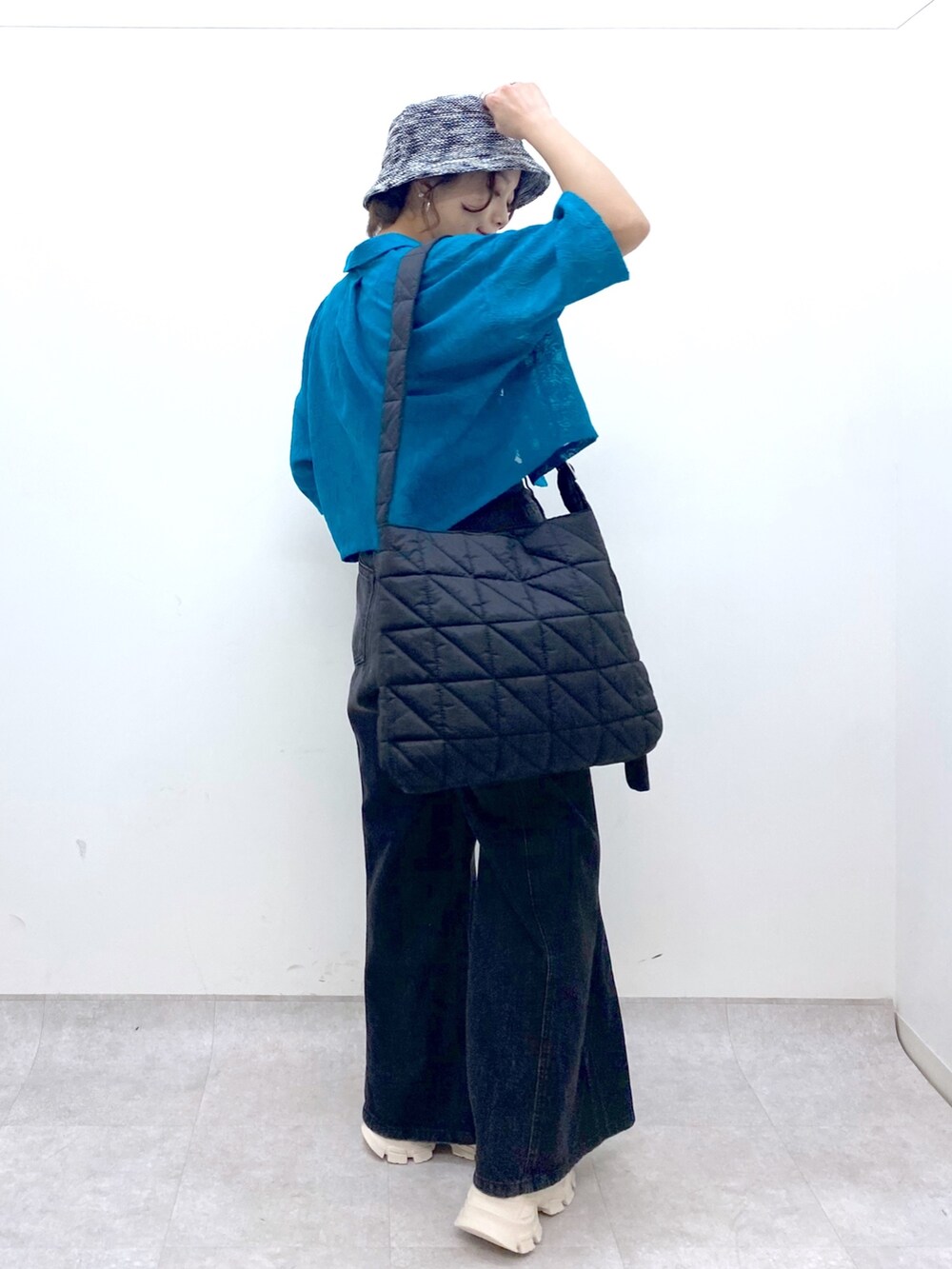 ブラック系のデニムパンツ、ブラック系のショルダーバッグ、ブルー系のタンクトップを着用したレディースの夏コーディネートの4枚目の写真