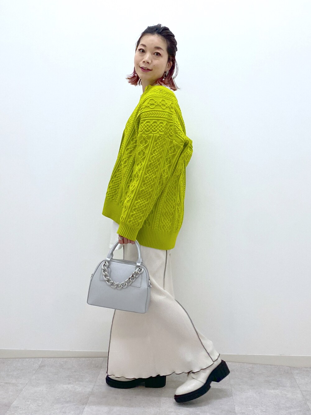 イエロー系のニット/セーター、ホワイト系のスカート、ホワイト系のローファーを着用したレディースの冬コーディネートの2枚目の写真