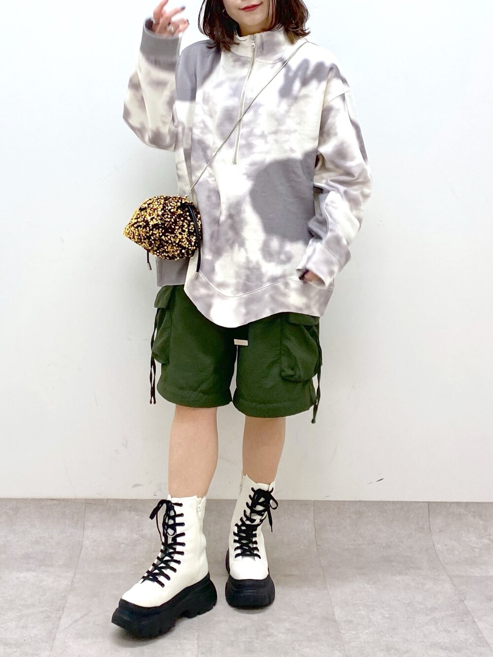 グリーン系のカーゴパンツ、ホワイト系のブーツ、ゴールド系のショルダーバッグを着用したレディースの冬コーディネートの3枚目の写真