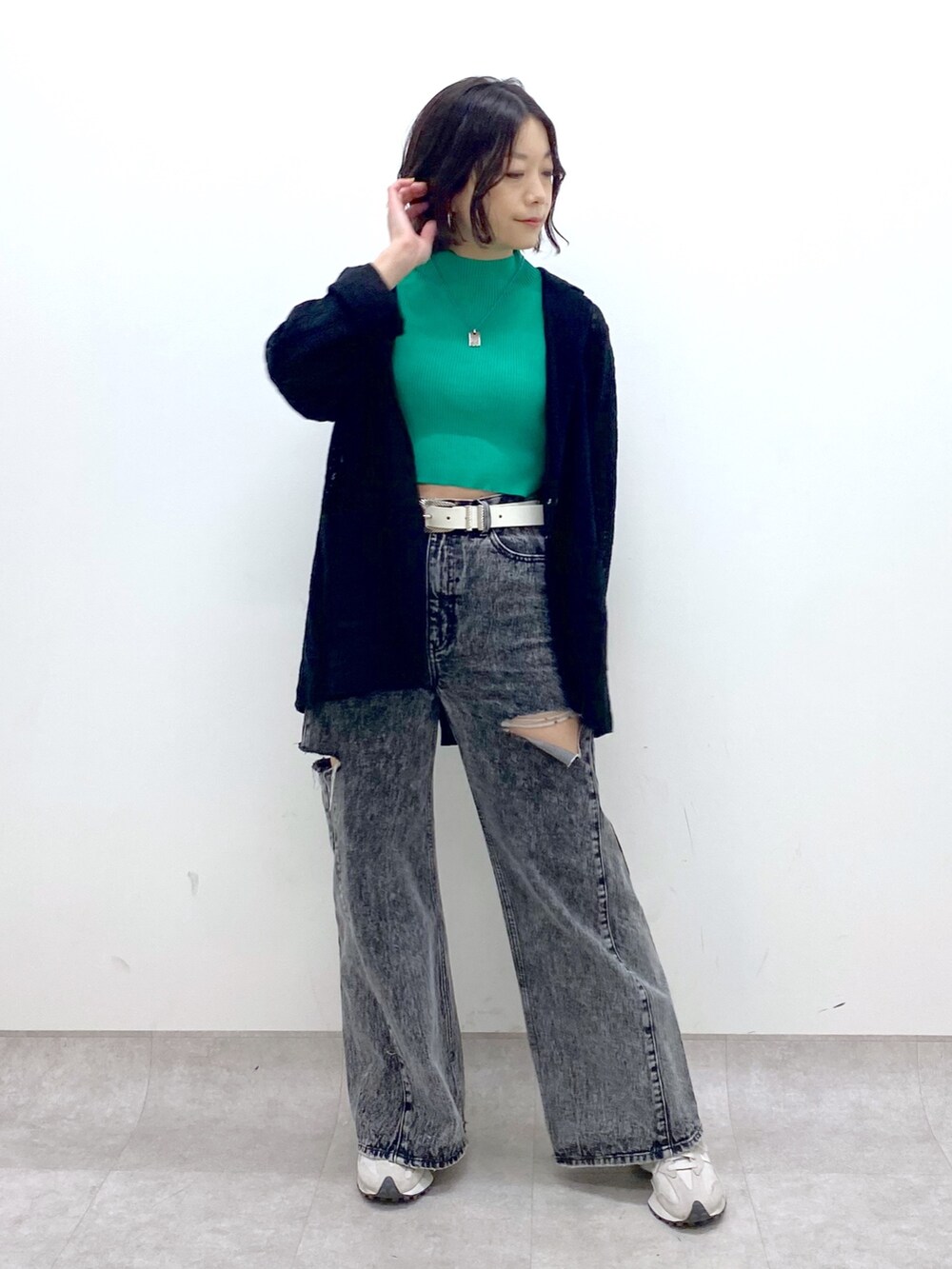 ブラック系のパンツ、ベージュ系のスニーカー、グリーン系のトップスを着用したレディースの春コーディネートの5枚目の写真