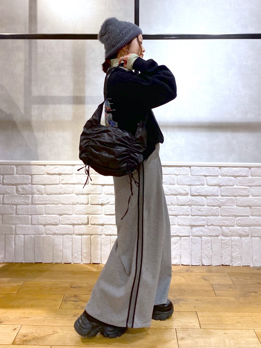 ブラック系のスウェット、グリーン系のショルダーバッグ、ブラック系のスラックスを着用したレディースの秋コーディネートの5枚目の写真