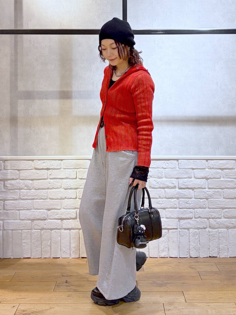 ブラック系のスニーカー、ブラック系のボストンバッグ、レッド系のカーディガン/ボレロを着用したレディースの春コーディネートの7枚目の写真