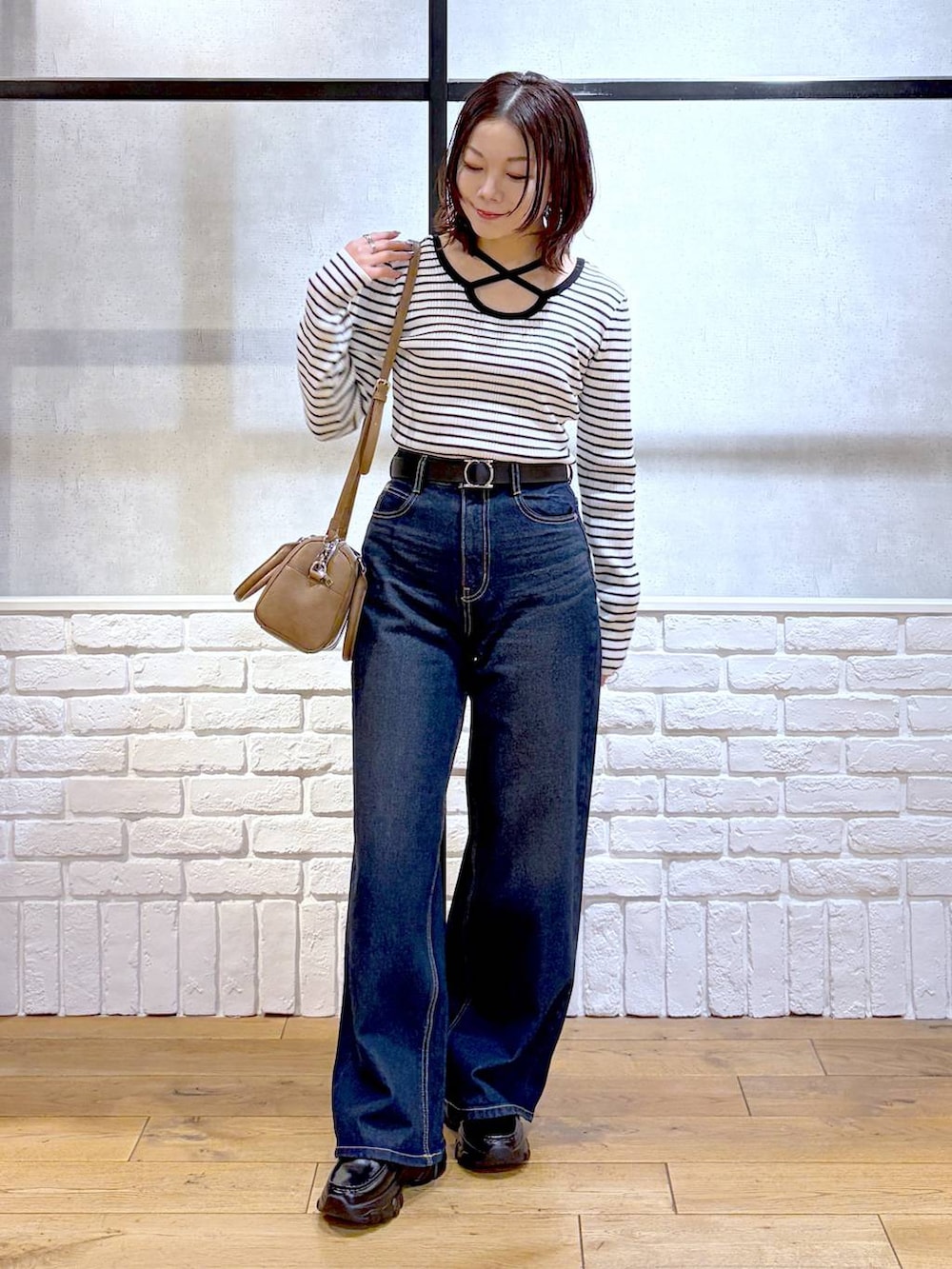 ブラック系のローファー、ブルー系のスラックス、ブラウン系のボストンバッグを着用したレディースの冬コーディネートの5枚目の写真