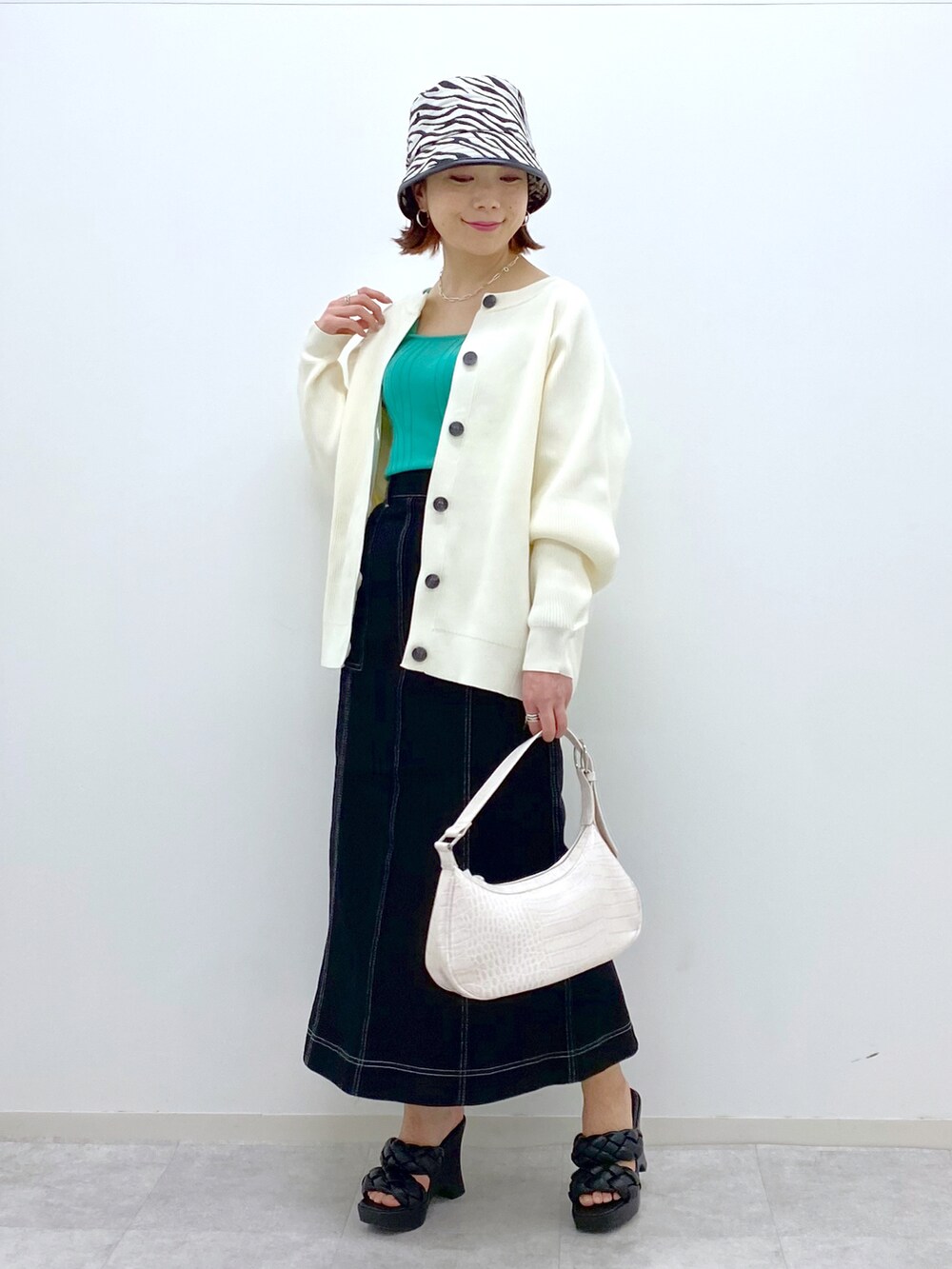 ホワイト系のカーディガン/ボレロ、グリーン系のタンクトップ、ホワイト系のショルダーバッグを着用したレディースの春コーディネートの2枚目の写真