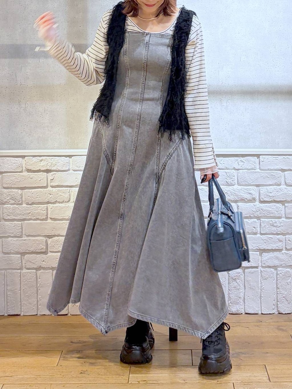 ブラック系のスニーカー、ブラック系のワンピース、ブルー系のショルダーバッグを着用したレディースの冬コーディネートの3枚目の写真