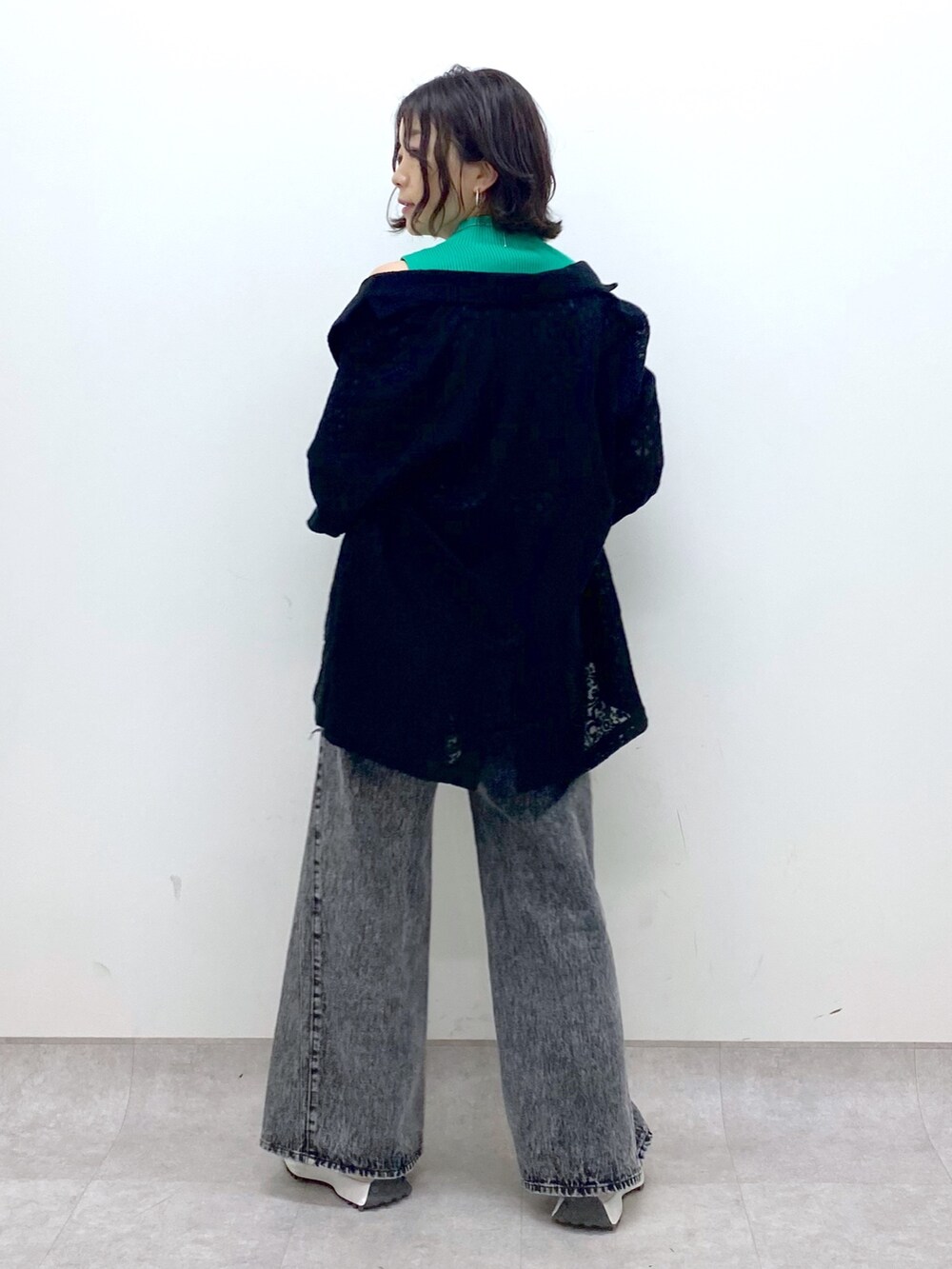 ブラック系のパンツ、ベージュ系のスニーカー、グリーン系のトップスを着用したレディースの春コーディネートの3枚目の写真