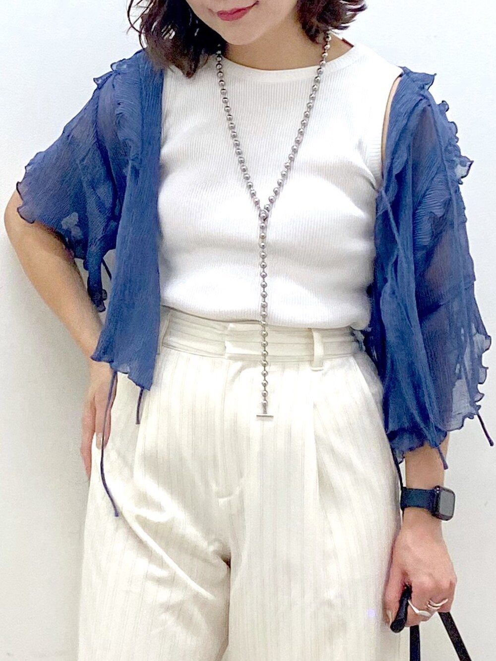 ホワイト系のスラックス、ブラック系のハンドバッグ、シルバー系のパンプスを着用したレディースの夏コーディネートの2枚目の写真