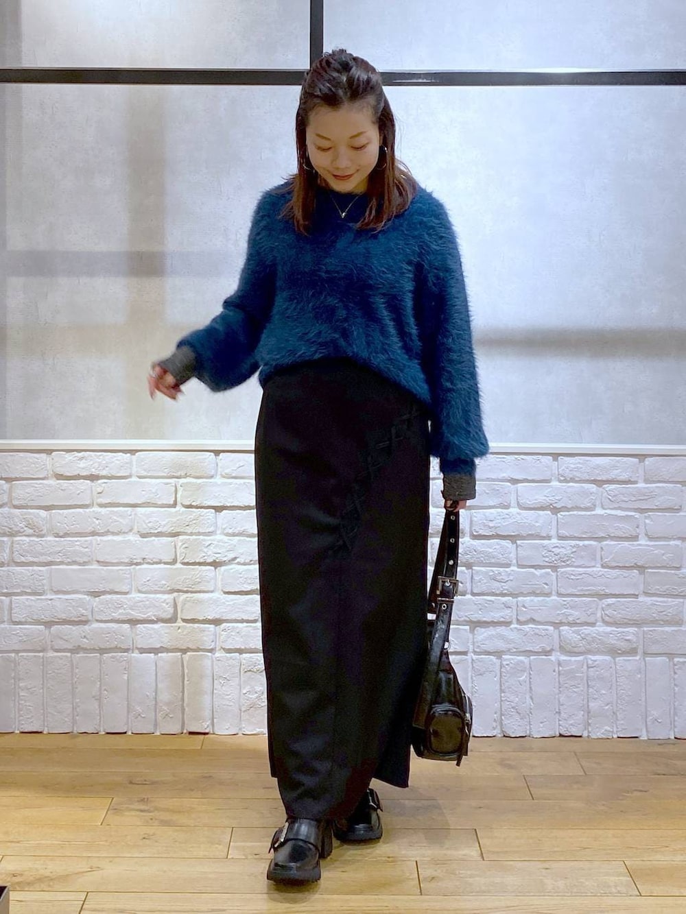 シルバー系のTシャツ/カットソー、ブラック系のブーツ、ブルー系のニット/セーターを着用したレディースの冬コーディネートの9枚目の写真