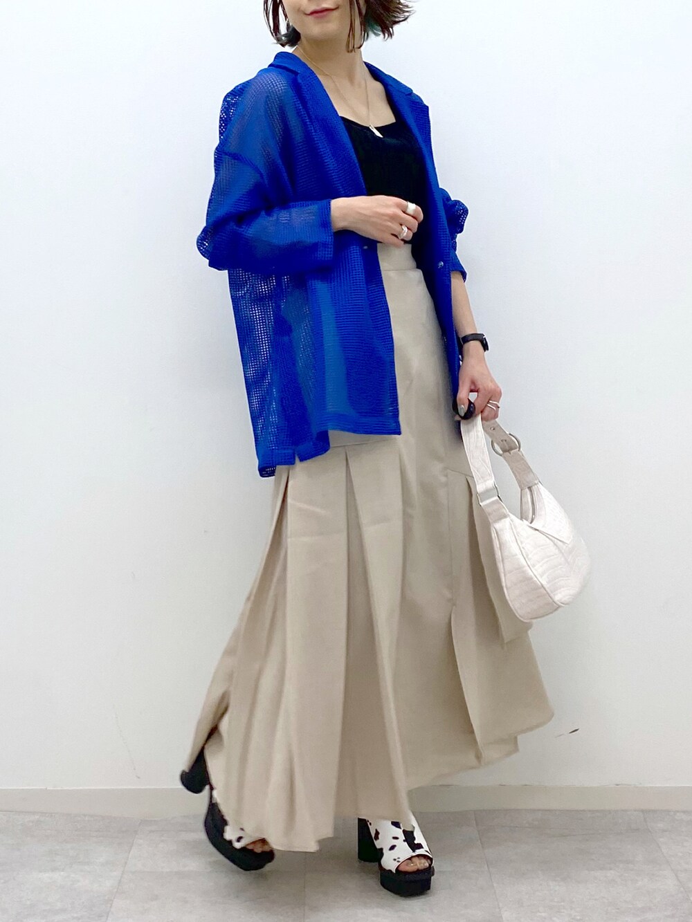 ブルー系のテーラードジャケット、ブラック系のタンクトップ、ベージュ系のスカートを着用したレディースの春コーディネートの5枚目の写真