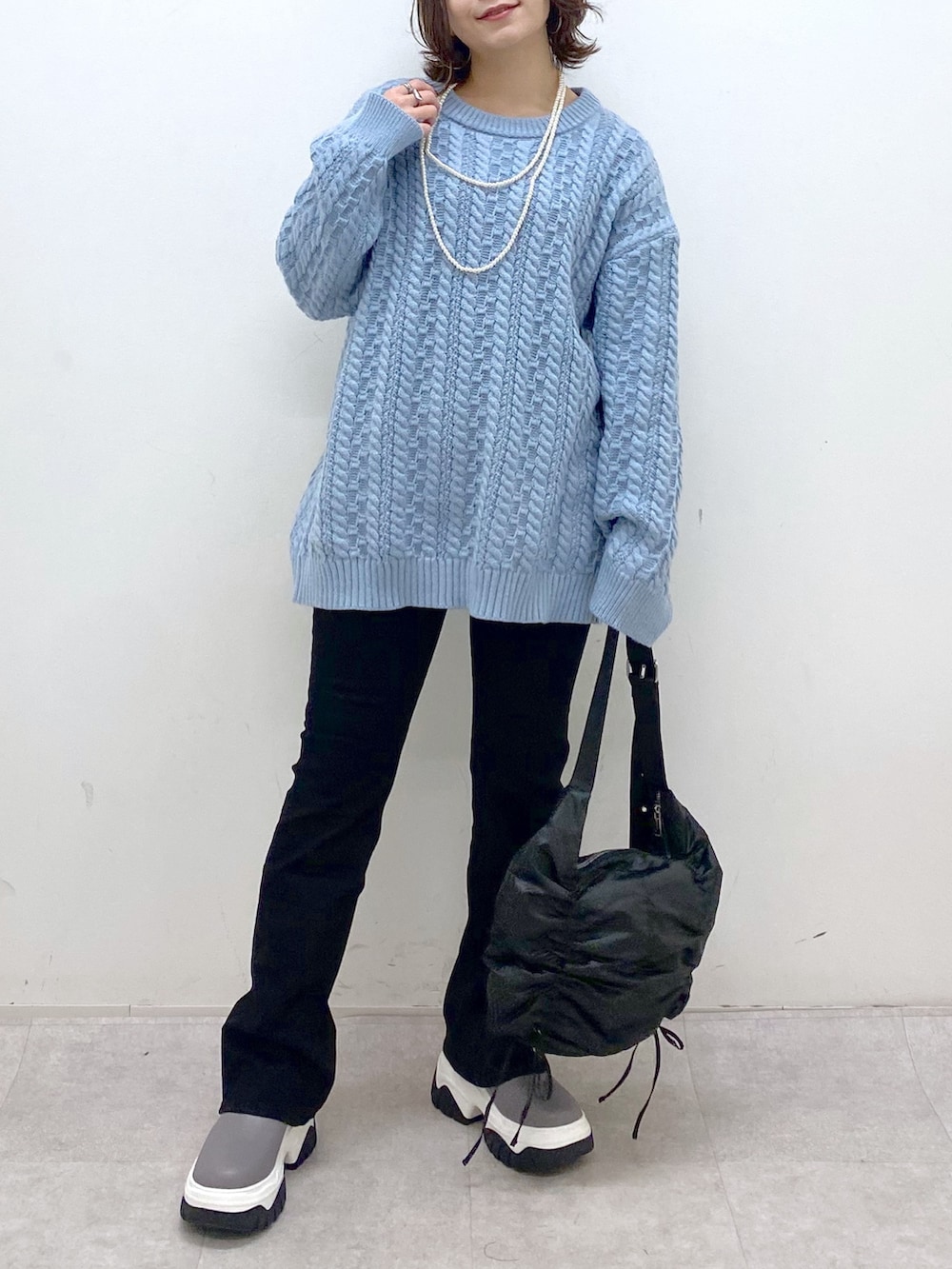 グリーン系のニット/セーター、ブラック系のショルダーバッグ、ブラック系のデニムパンツを着用したレディースの冬コーディネートの3枚目の写真