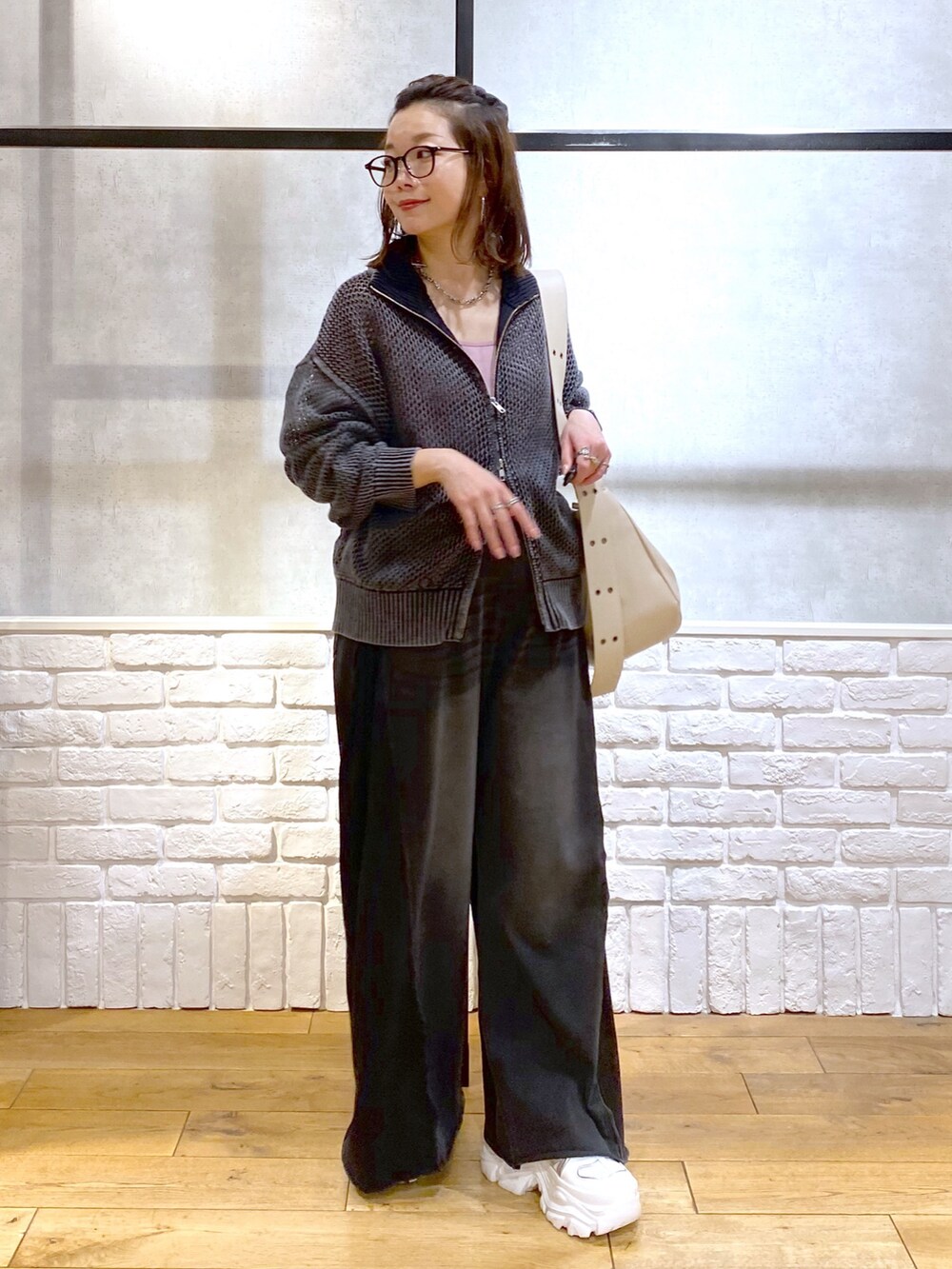 ピンク系のキャミソール、ブラック系のニット/セーター、ブラック系のデニムパンツを着用したレディースの春コーディネートの4枚目の写真