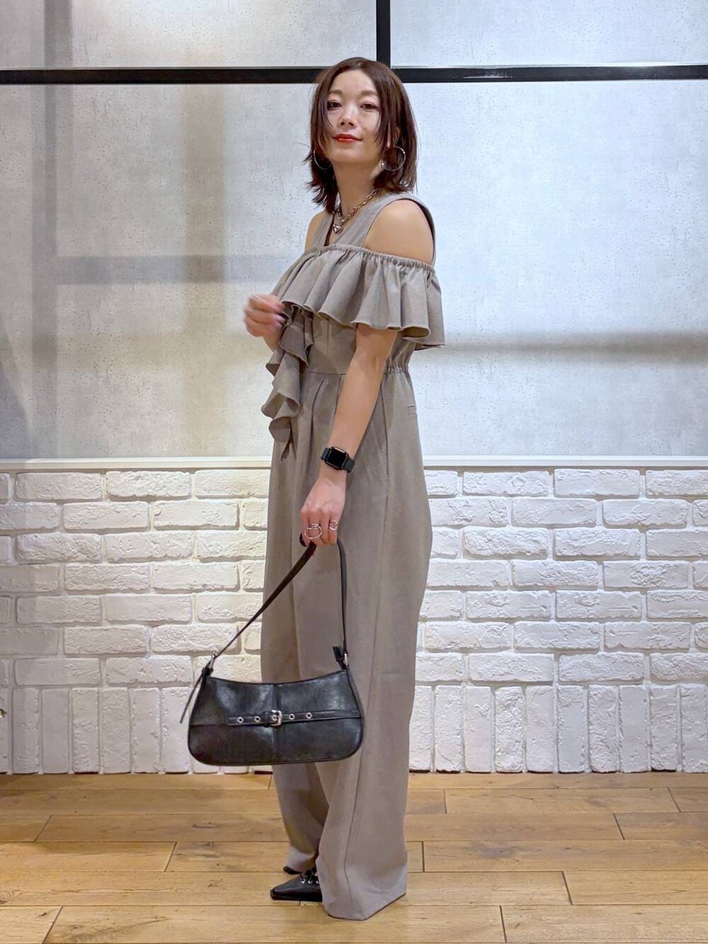 ブラック系のハンドバッグ、ブラック系のサンダル、ベージュ系のサロペット/オーバーオールを着用したレディースの春コーディネートの5枚目の写真