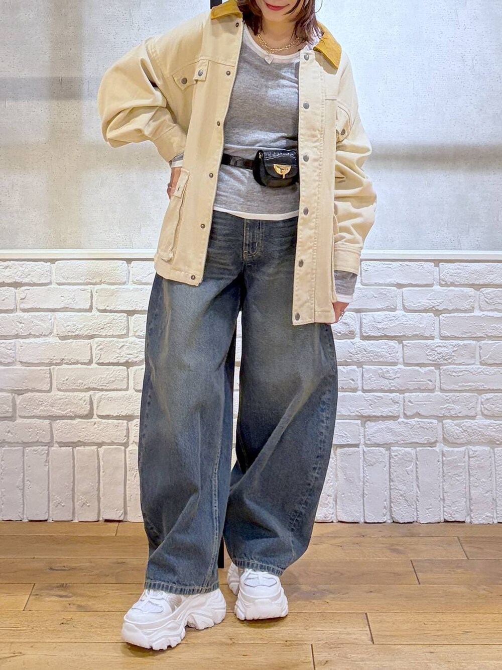 ホワイト系のスニーカー、ブラック系のボディバッグ/ウエストポーチ、ブルー系のデニムパンツを着用したレディースの冬コーディネートの2枚目の写真