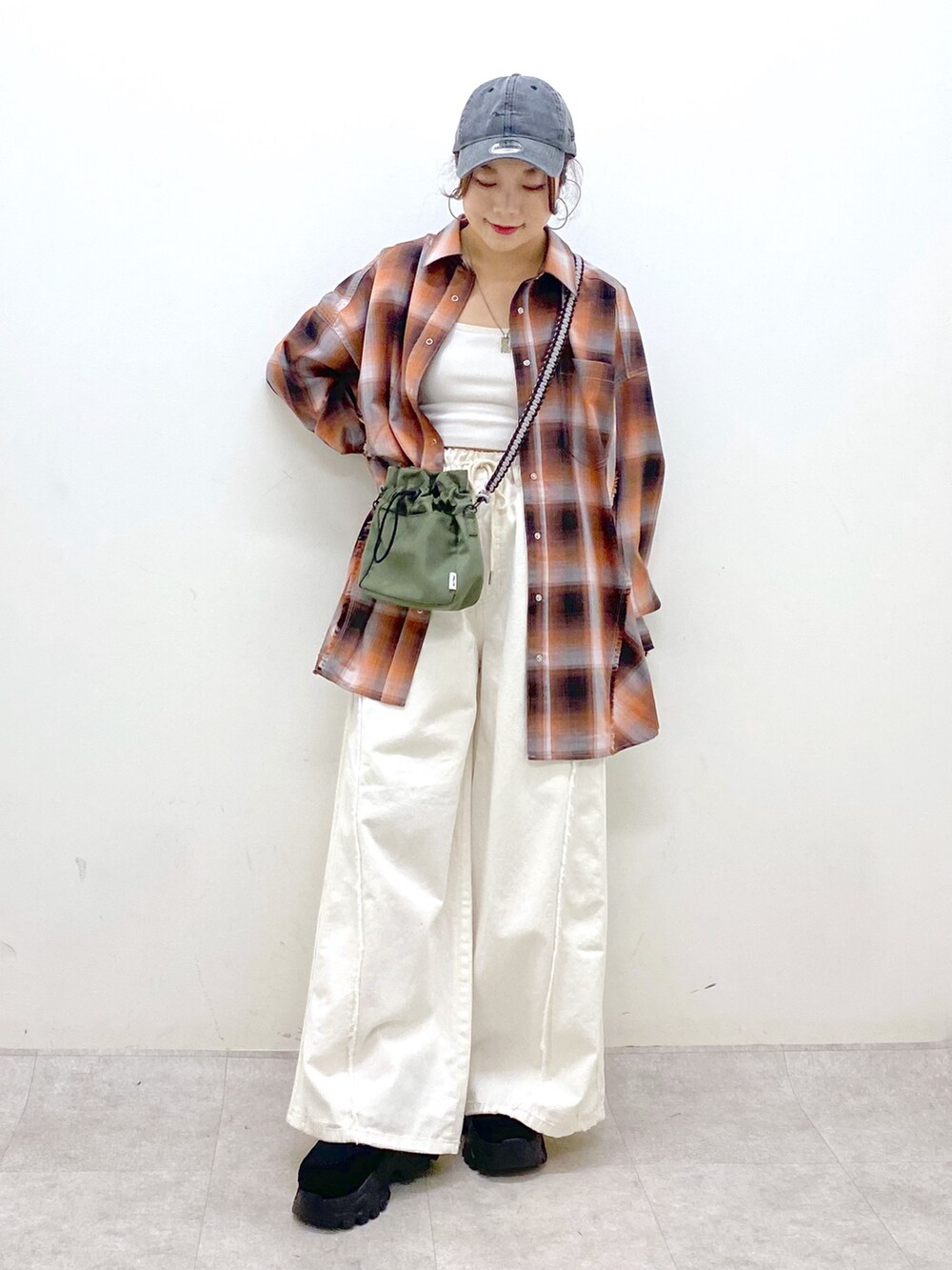 ホワイト系のデニムパンツ、ブラック系のスニーカー、グリーン系のショルダーバッグを着用したレディースの夏コーディネートの9枚目の写真