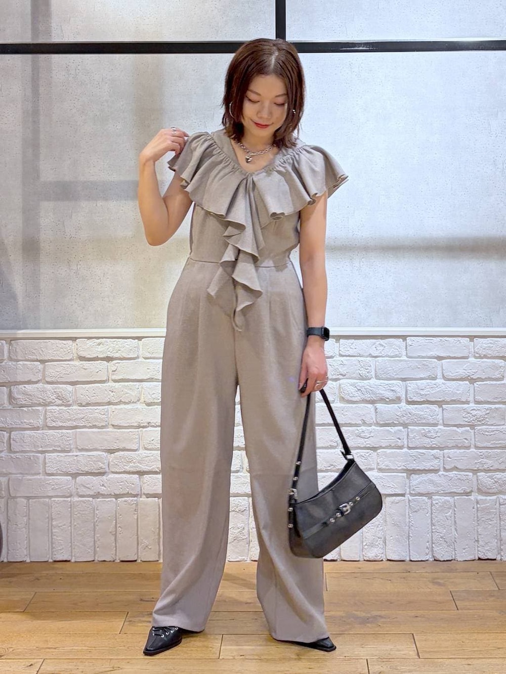 ブラック系のハンドバッグ、ブラック系のサンダル、ベージュ系のサロペット/オーバーオールを着用したレディースの春コーディネートの6枚目の写真
