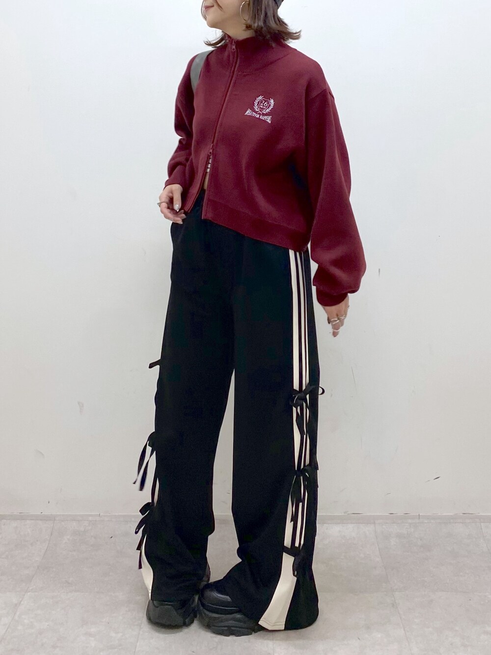 レッド系のニット/セーター、ブラック系のその他パンツ、ブラック系のブーツを着用したレディースの秋コーディネートの4枚目の写真