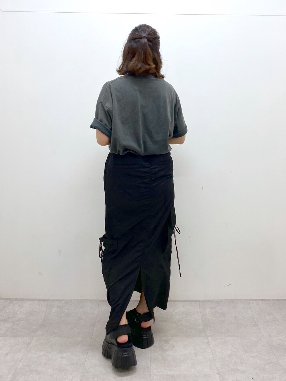 グレー系のTシャツ/カットソー、ブラック系のスカート、ブラック系のスニーカーを着用したレディースの夏コーディネートの6枚目の写真