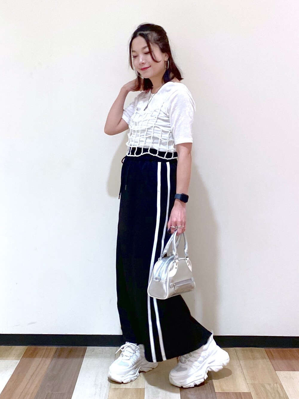 ブラック系のスカート、シルバー系のショルダーバッグ、ホワイト系のスニーカーを着用したレディースの夏コーディネートの9枚目の写真