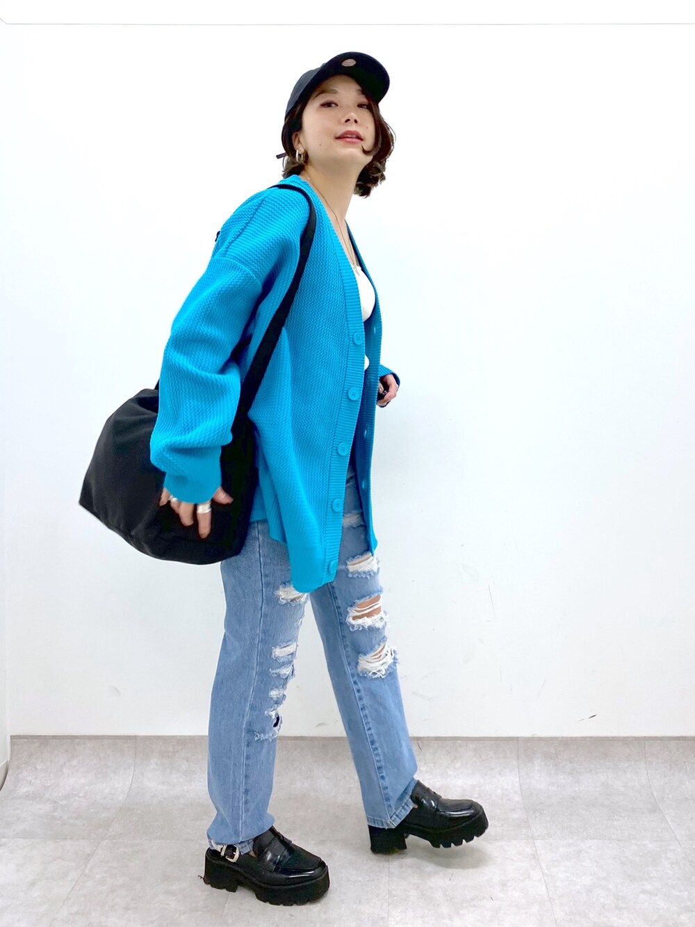 ブラック系のバッグ、ブルー系のパンツ、ブラック系のローファーを着用したレディースの春コーディネートの3枚目の写真