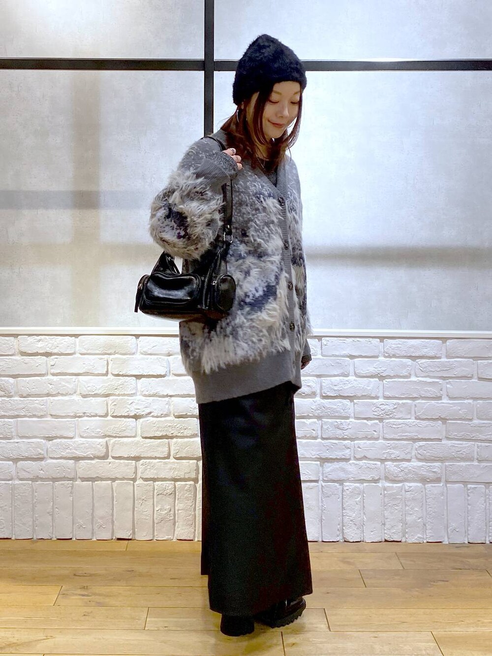 シルバー系のTシャツ/カットソー、ブラック系のブーツ、ブラック系のスカートを着用したレディースの冬コーディネートの7枚目の写真