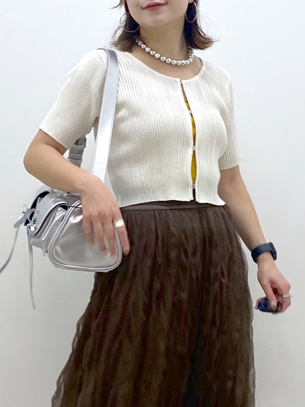 ブラウン系のスカート、ブラック系のサンダル、シルバー系のショルダーバッグを着用したレディースの夏コーディネートの2枚目の写真