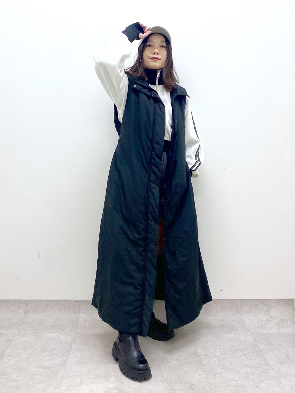 ブラック系のベスト、ブラック系のブーツ、ホワイト系のジャージを着用したレディースの秋コーディネートの2枚目の写真