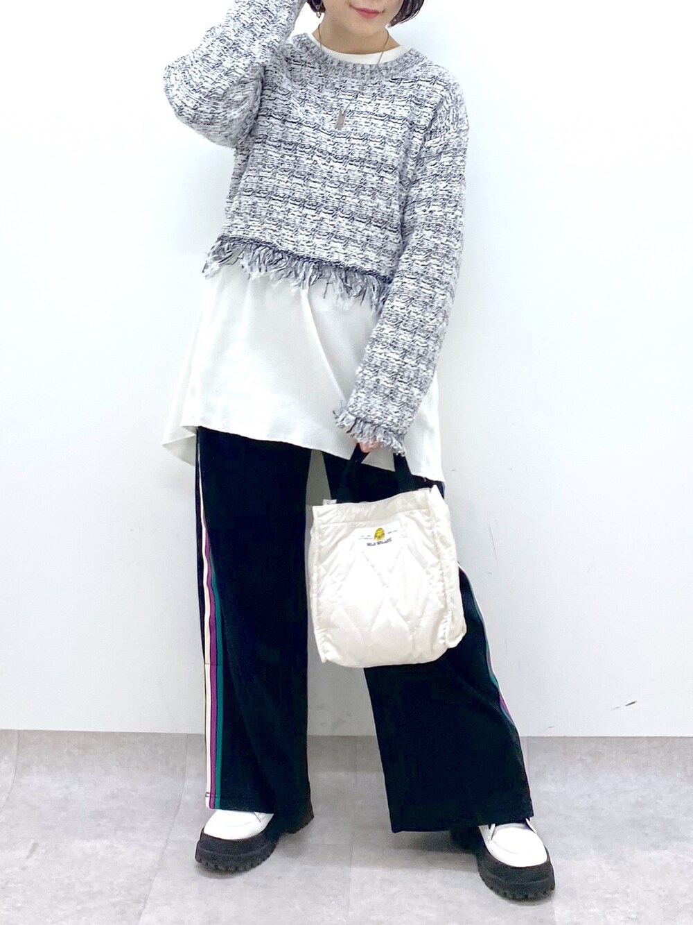 ホワイト系のニット/セーター、ブラック系のスウェットパンツ、ホワイト系のシューズを着用したレディースの春コーディネートの5枚目の写真
