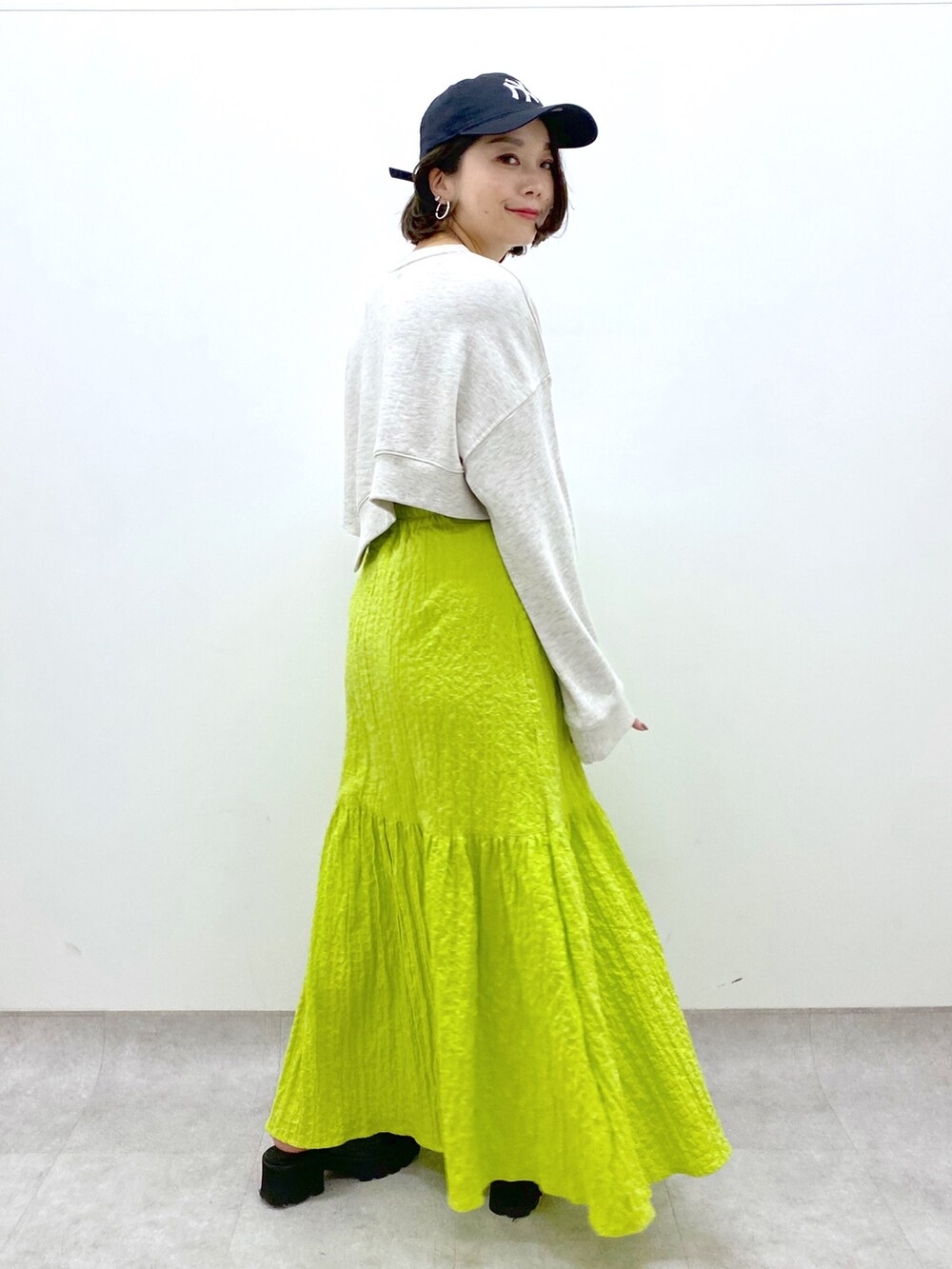 イエロー系のスカート、ベージュ系のトップス、ブラック系のローファーを着用したレディースの春コーディネートの3枚目の写真