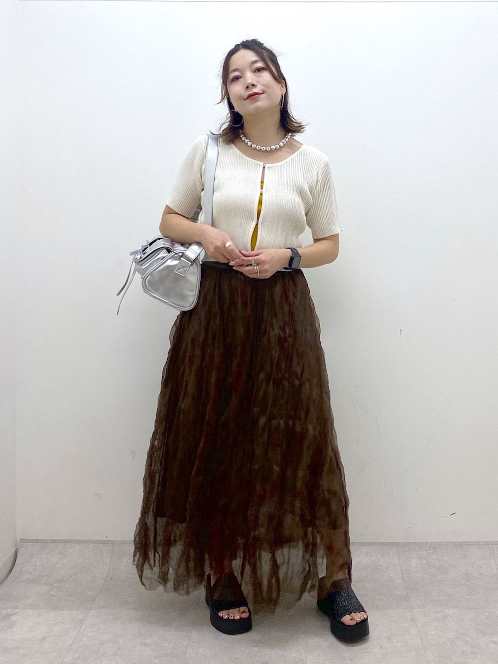 ブラウン系のスカート、ブラック系のサンダル、シルバー系のショルダーバッグを着用したレディースの夏コーディネートの9枚目の写真