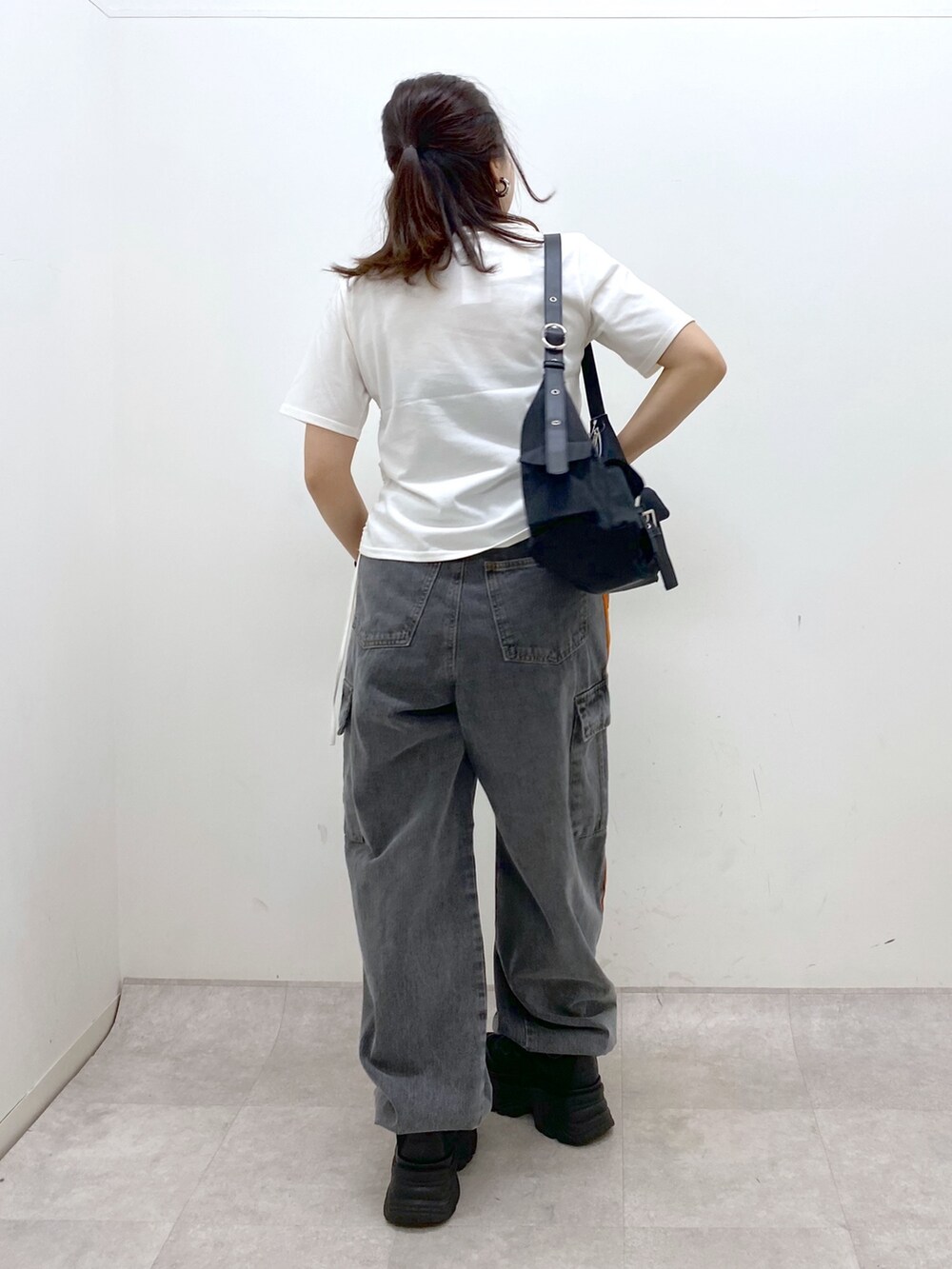 ホワイト系のTシャツ/カットソー、ブラック系のデニムパンツ、ブラック系のスニーカーを着用したレディースの春コーディネートの6枚目の写真