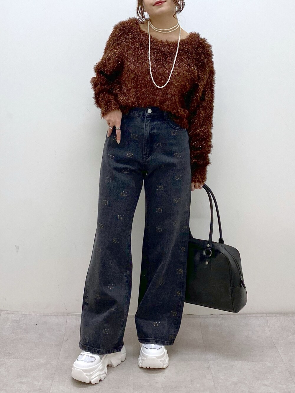 ブラウン系のニット/セーター、ブラック系のボストンバッグ、ホワイト系のスニーカーを着用したレディースの冬コーディネートの3枚目の写真