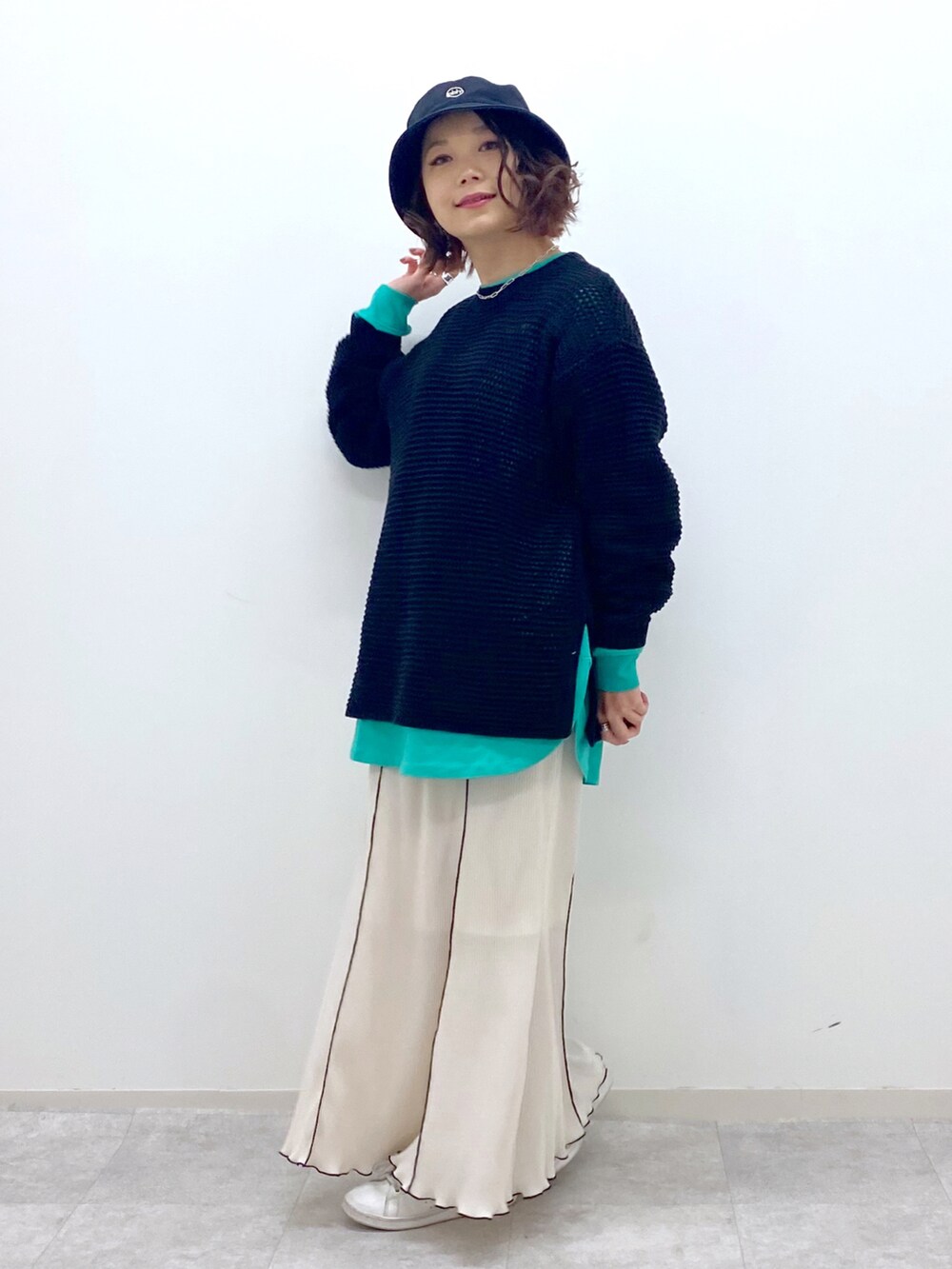 ブラック系のニット/セーター、グリーン系のTシャツ/カットソー、ホワイト系のスカートを着用したレディースの春コーディネートの2枚目の写真