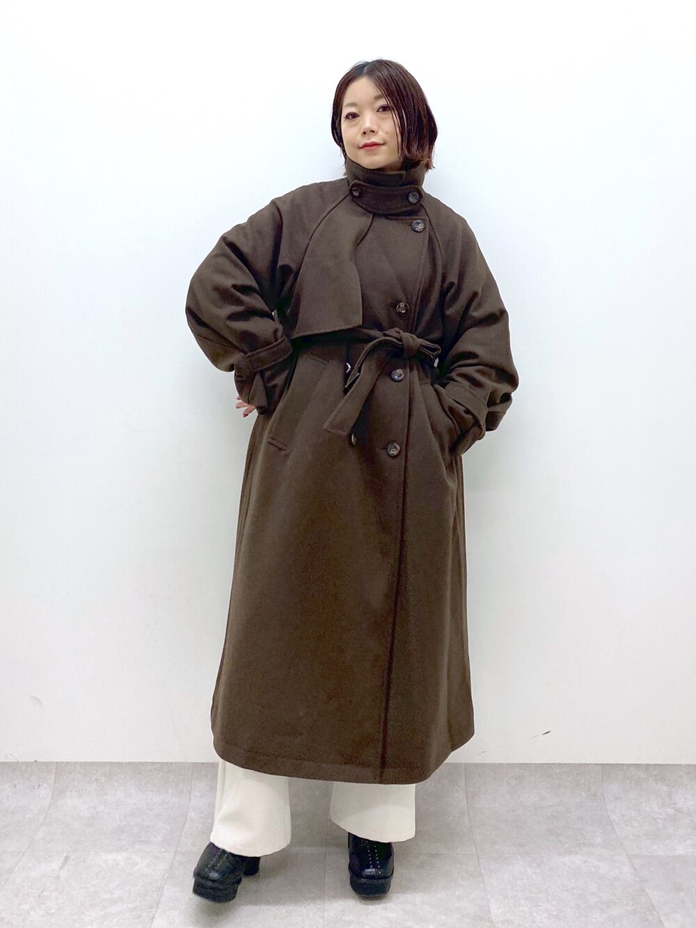 ブラック系のトップス、オレンジ系のトップス、ホワイト系のパンツを着用したレディースの秋コーディネートの3枚目の写真