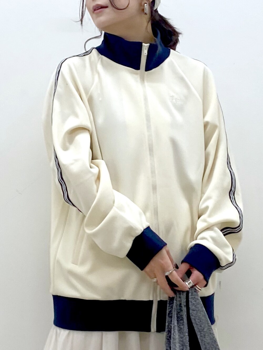 ホワイト系のセットアップ、ブラック系のトートバッグ、ホワイト系のスカートを着用したレディースの冬コーディネートの2枚目の写真