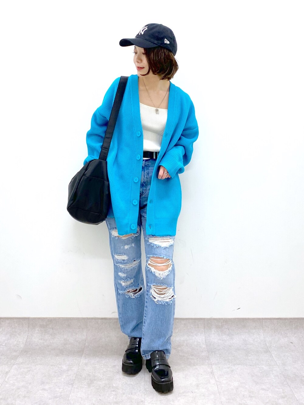 ブラック系のバッグ、ブルー系のパンツ、ブラック系のローファーを着用したレディースの春コーディネートの2枚目の写真