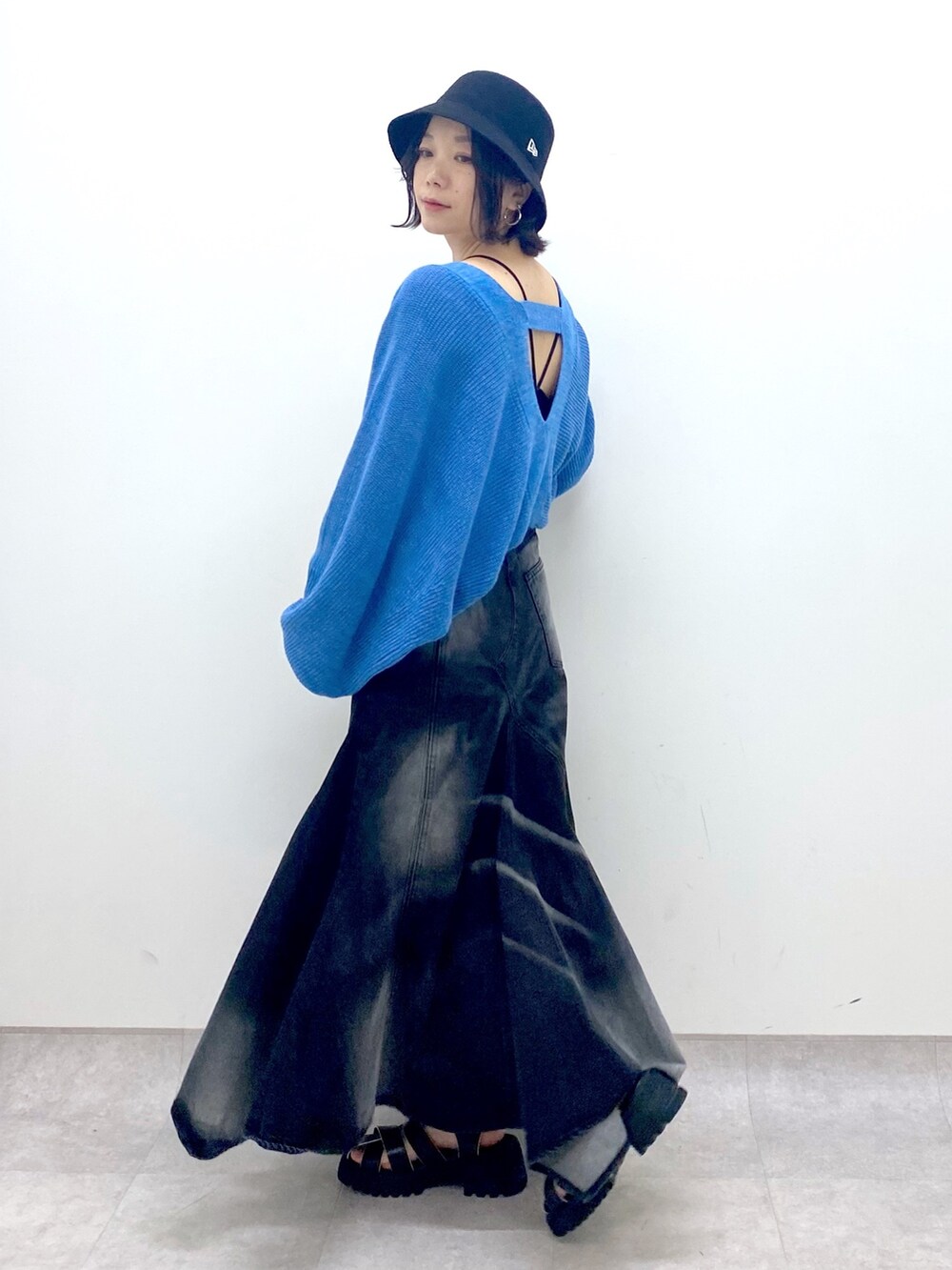 ブラック系のスカート、ブルー系のトップス、ブラック系のサンダルを着用したレディースの春コーディネートの2枚目の写真