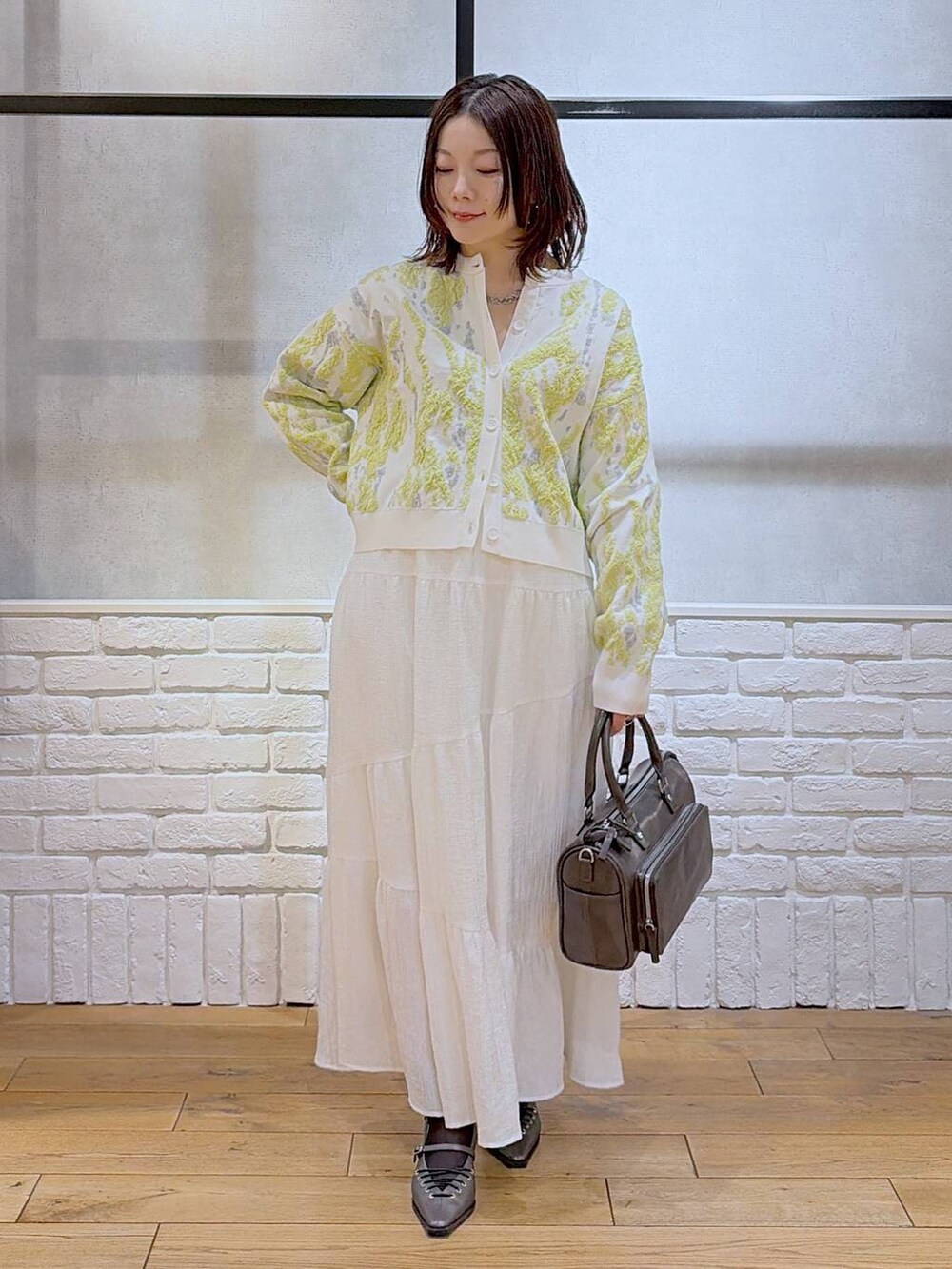 グレー系のショルダーバッグ、ブラウン系のサンダル、ホワイト系のスカートを着用したレディースの冬コーディネートの4枚目の写真