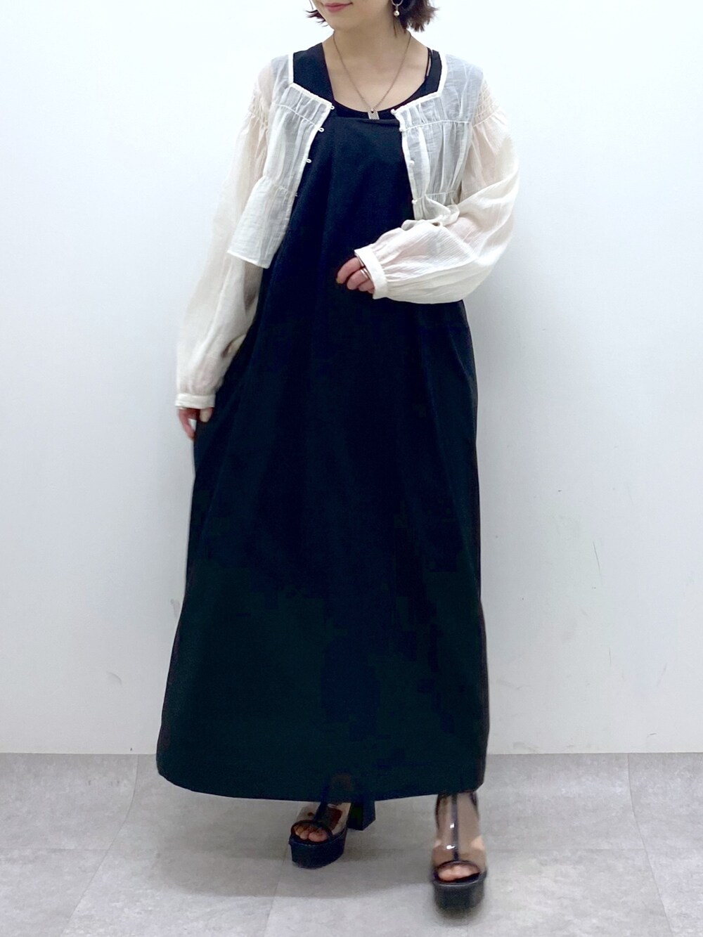 ブラック系のジャンパースカート、ホワイト系のシャツ/ブラウス、その他のサンダルを着用したレディースの夏コーディネートの6枚目の写真