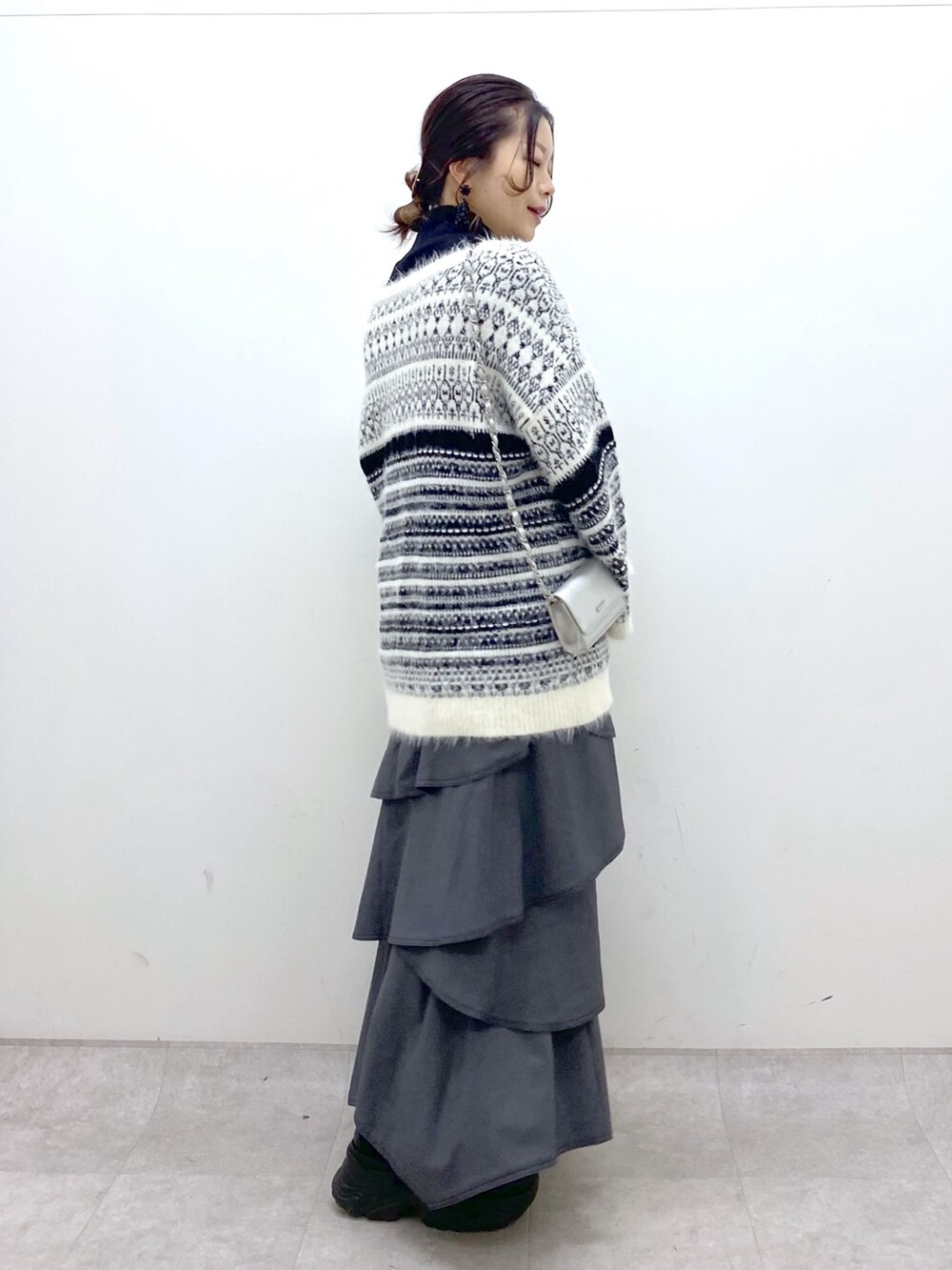 ホワイト系のカーディガン/ボレロ、グレー系のスカート、ブラック系のスニーカーを着用したレディースの冬コーディネートの3枚目の写真