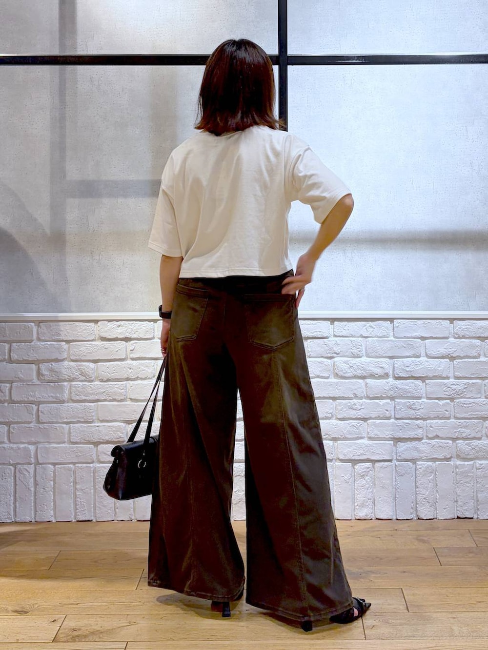 ブラウン系のデニムパンツ、ホワイト系のTシャツ/カットソー、ブラック系のサンダルを着用したレディースの夏コーディネートの7枚目の写真