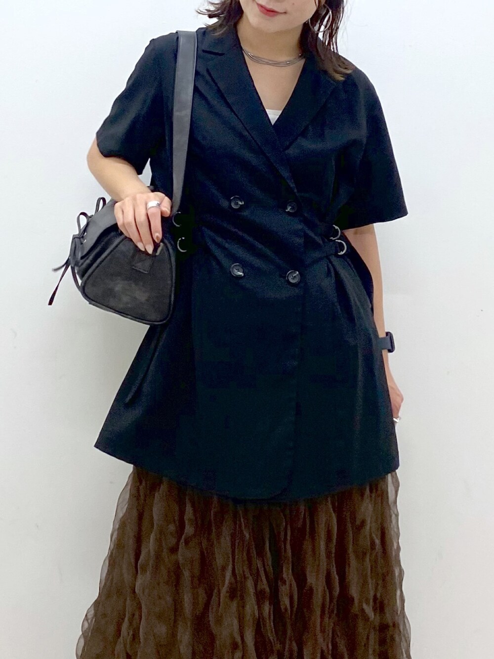 ブラック系のテーラードジャケット、ブラウン系のスカート、ブラック系のショルダーバッグを着用したレディースの夏コーディネートの2枚目の写真