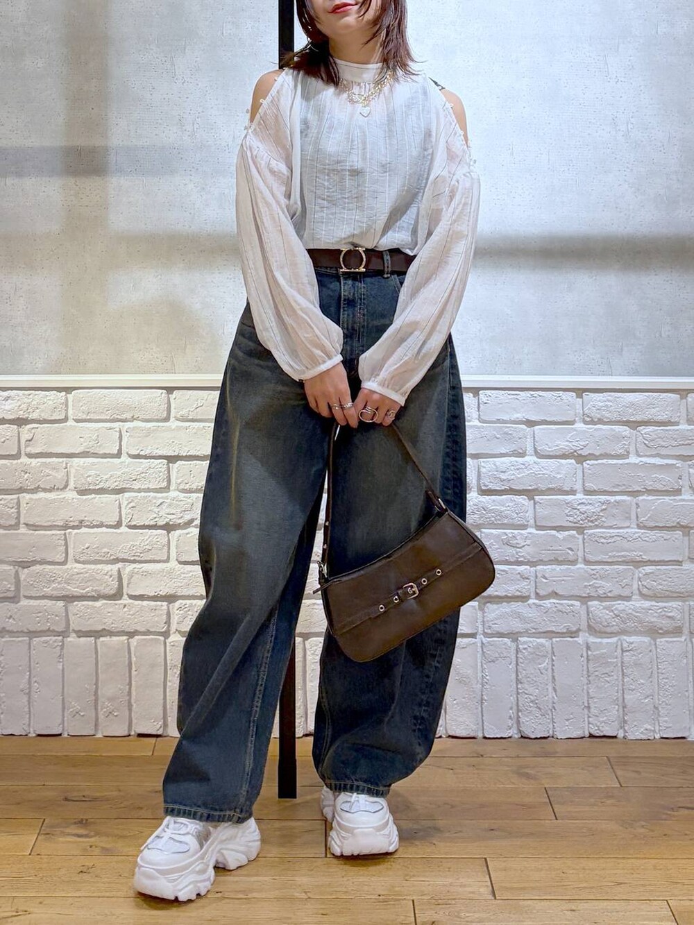 ホワイト系のスニーカー、ブルー系のデニムパンツ、ブラウン系のハンドバッグを着用したレディースの春コーディネートの3枚目の写真
