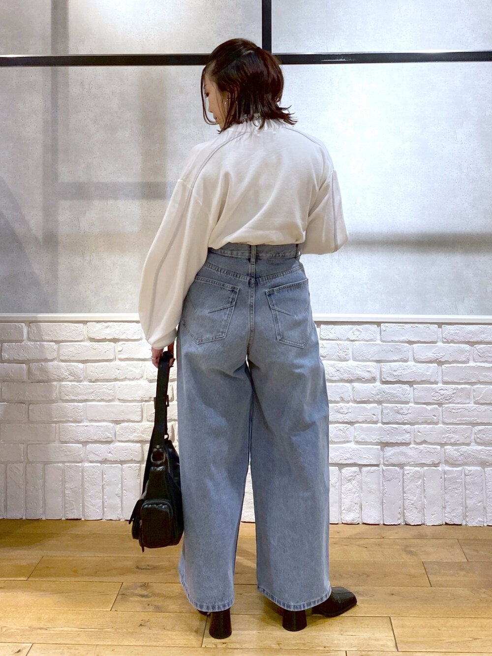 ホワイト系のニット/セーター、ブルー系のデニムパンツ、ブラック系のショルダーバッグを着用したレディースの冬コーディネートの6枚目の写真