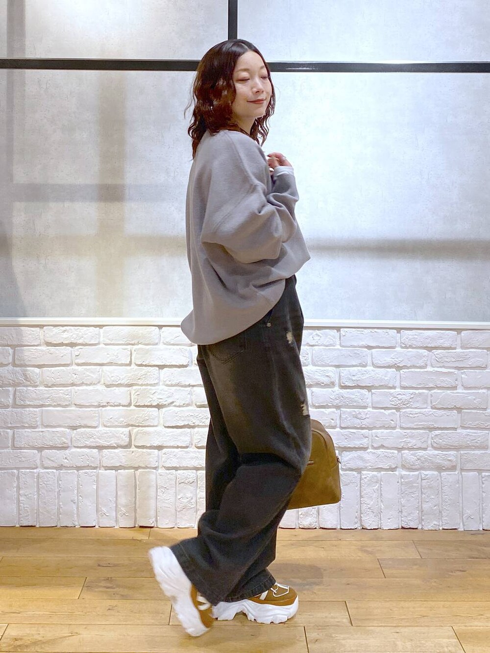 ベージュ系のスニーカー、イエロー系のボストンバッグ、ブラック系のデニムパンツを着用したレディースの秋コーディネートの7枚目の写真