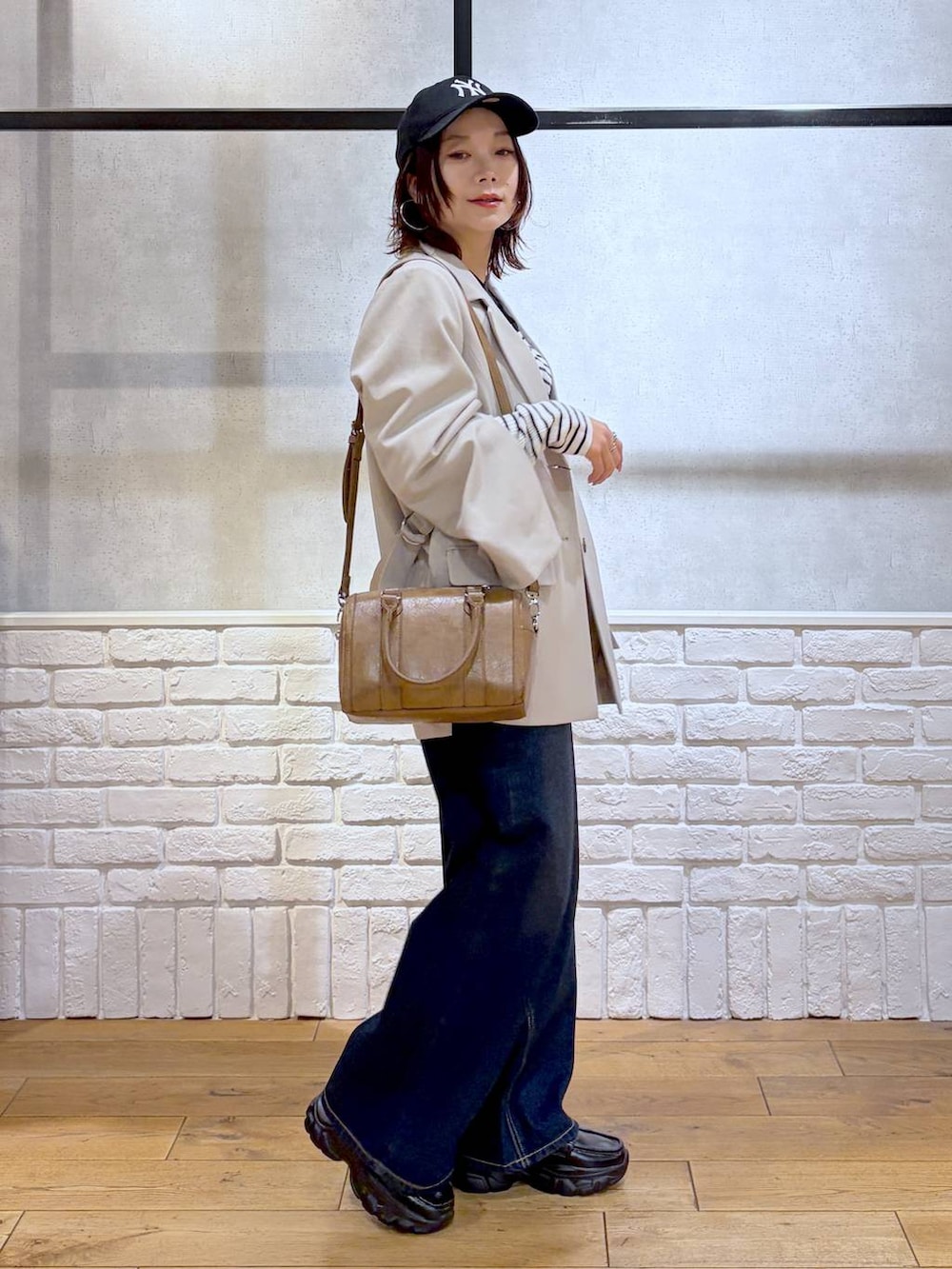 ブラック系のローファー、ブルー系のスラックス、ブラウン系のボストンバッグを着用したレディースの冬コーディネートの9枚目の写真