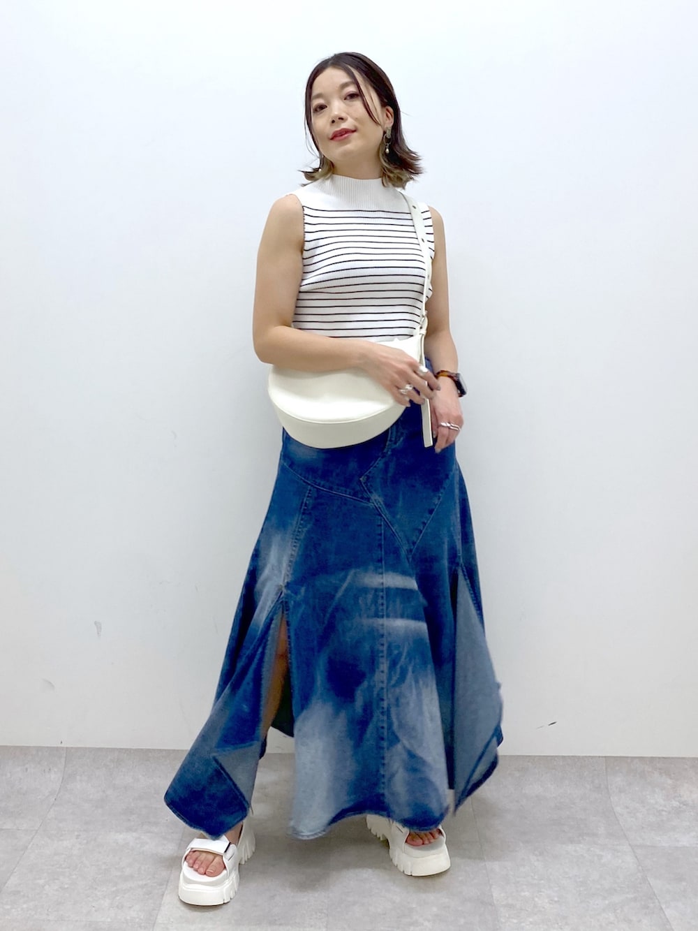 ホワイト系のショルダーバッグ、ブルー系のスカート、ホワイト系のTシャツ/カットソーを着用したレディースの夏コーディネートの2枚目の写真