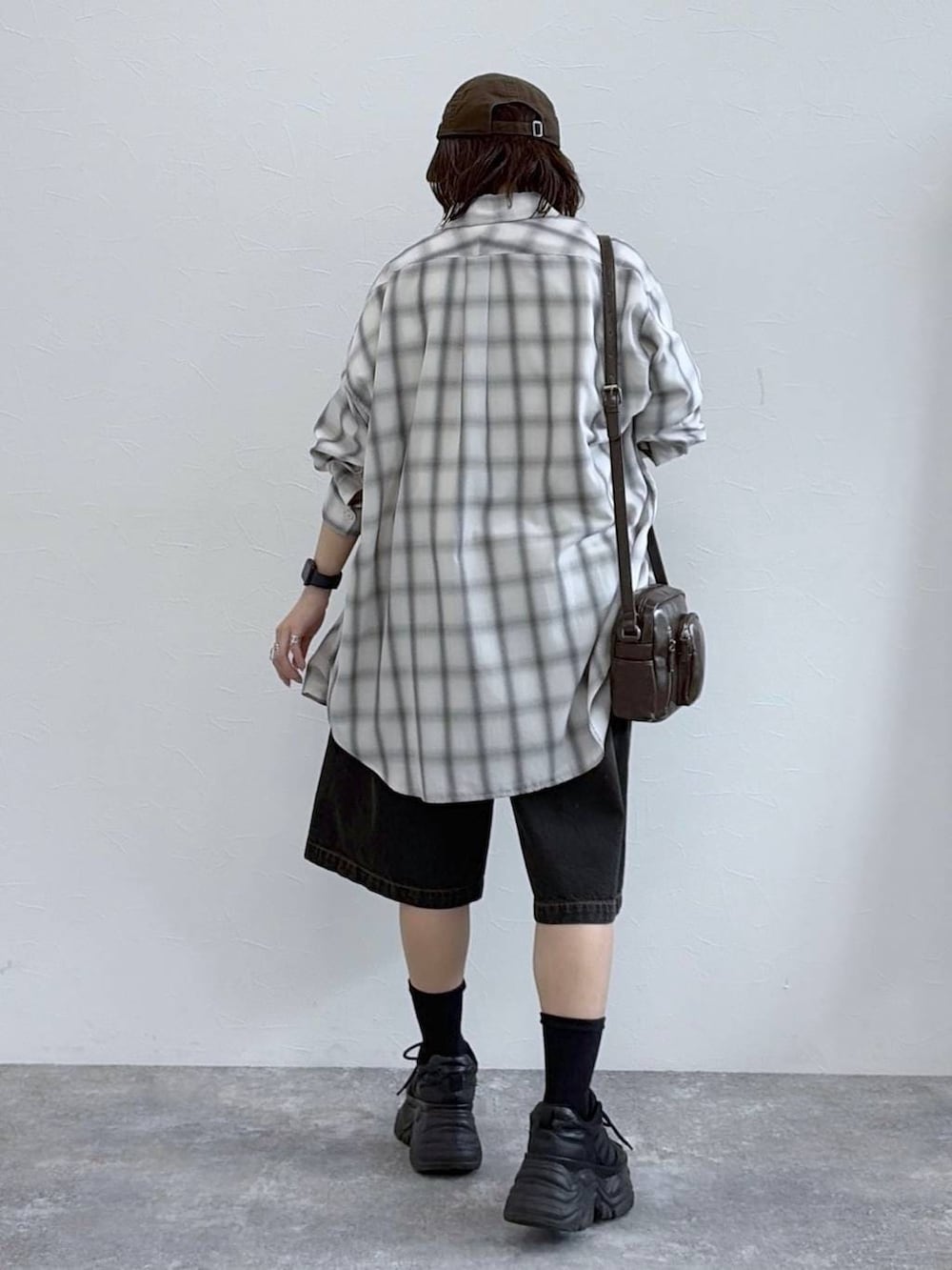 ブラック系のスニーカー、ブラウン系のショルダーバッグ、ホワイト系のシャツ/ブラウスを着用したレディースの春コーディネートの4枚目の写真