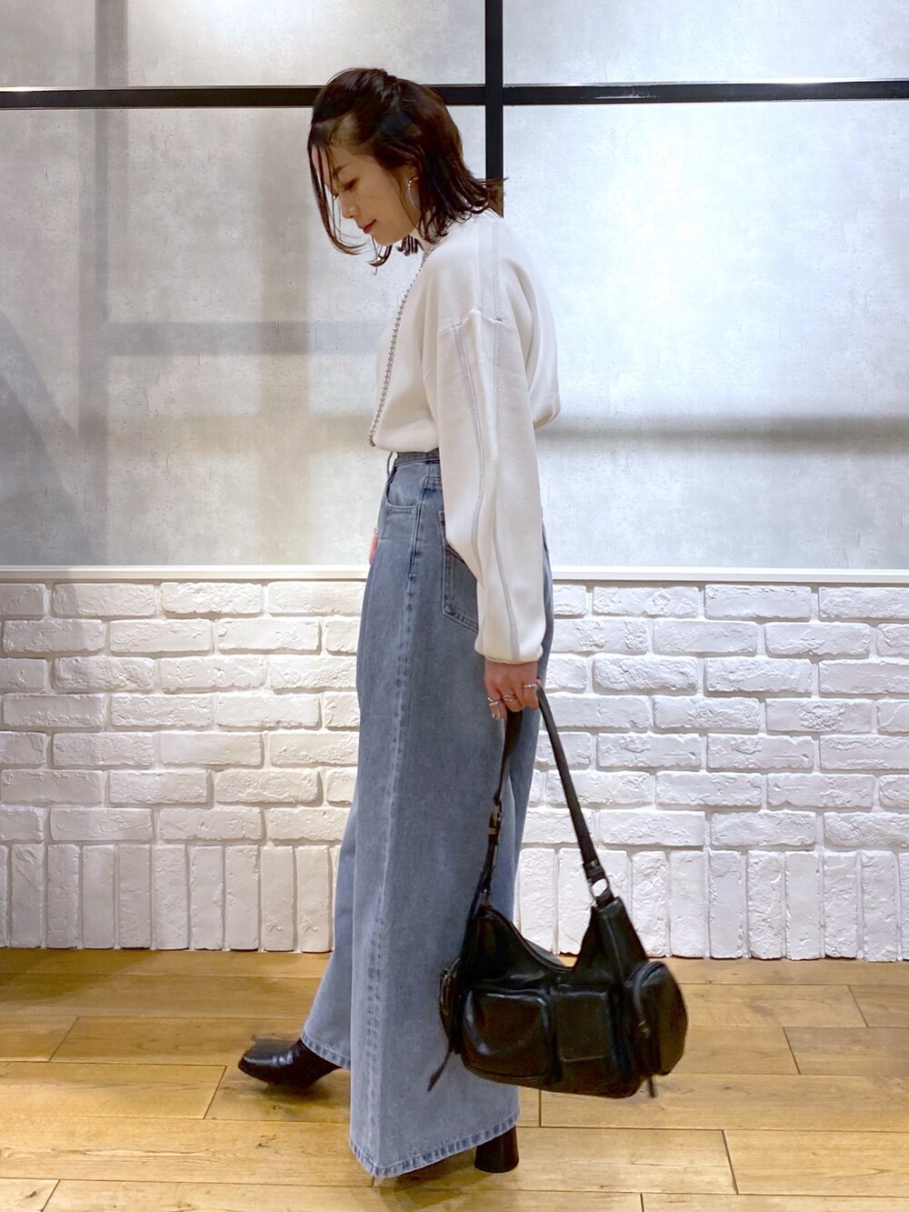 ホワイト系のニット/セーター、ブルー系のデニムパンツ、ブラック系のショルダーバッグを着用したレディースの冬コーディネートの5枚目の写真