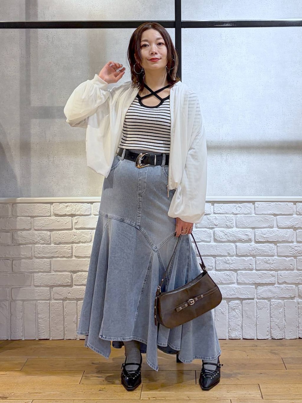 ブラウン系のハンドバッグ、ホワイト系のニット/セーター、ブラック系のサンダルを着用したレディースの春コーディネートの9枚目の写真